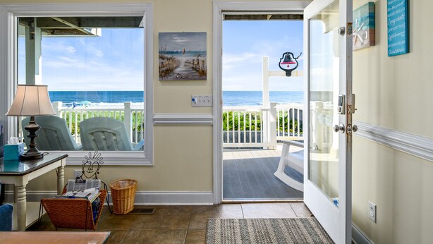 A room with a view of the ocean, a door leading to a balcony, a lamp, a chair, and a basket. - "Sundance" - Oceanfront Home w/ Private Pool, 5 Bedrooms / 4.5 Bathrooms (Holden Beach)