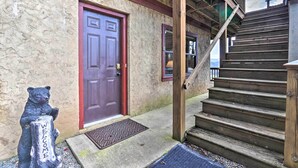 A wooden staircase leading to a red door with a welcome sign on a tree stump. - Smoky Mountain Retreat w/ Hot Tub, Arcade Games (Pigeon Forge)