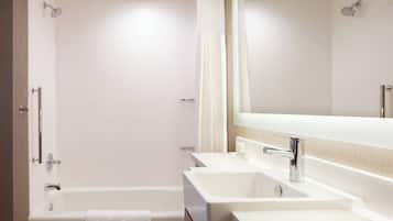 Un baño moderno con bañera, dos lavamanos y un espejo grande.