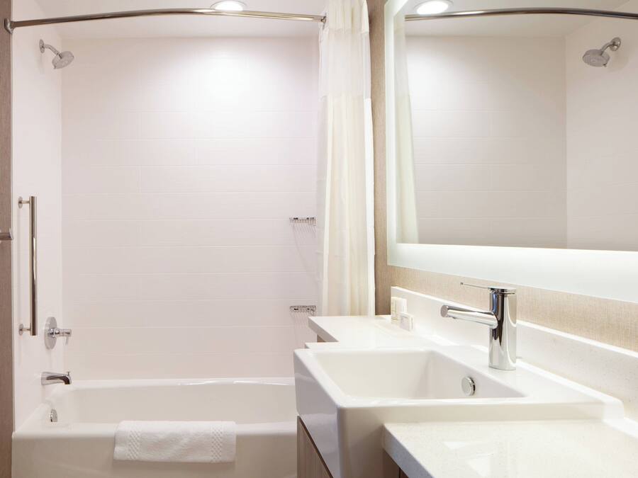 Un baño moderno con bañera, dos lavamanos y un espejo grande.