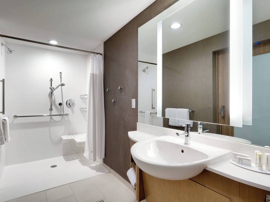 Une salle de bain moderne avec une douche à l’italienne, un grand miroir et un lavabo blanc.