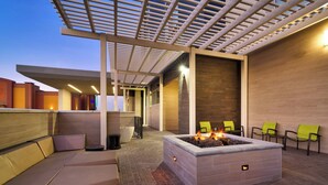 Un espace extérieur aménagé avec un foyer, des bancs rembourrés et une structure en forme de pergola.