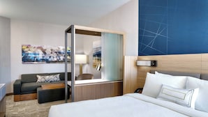 Une chambre d’hôtel avec un lit, un canapé, un bureau, un miroir et un tableau au mur.
