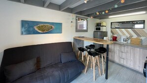 A modern kitchen with a bar area, a sofa, and a painting on the wall. - Patio Villa 20m from the beach with terrace and parking (Capbreton)
