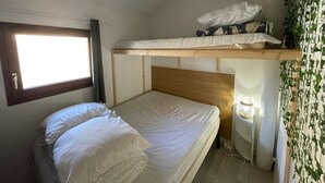 A bunk bed room with a window, a bedside table with a lamp, and a wall with green leafy wallpaper. - Patio Villa 20m from the beach with terrace and parking (Capbreton)