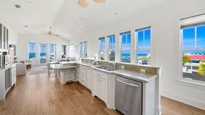A spacious kitchen with a large island, white cabinetry, and a view of the ocean. - 🌺 Aloha Beaches Gulf-Front Retreat, Pool, Steps to Beach, Sleeps 14 (Panama City Beach)