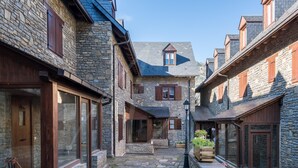 A stone building with wooden shutters, a stone pathway, and a view of the surrounding landscape. - Casa Eth Gauèc (Betrén)