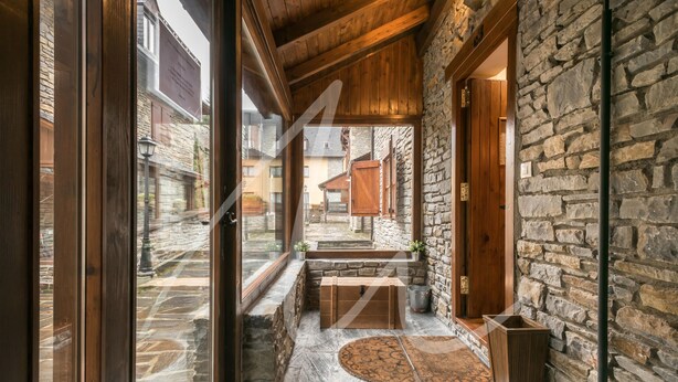A stone-walled interior with a wooden bench, a trash bin, and a rug. - Casa Eth Gauèc (Betrén)