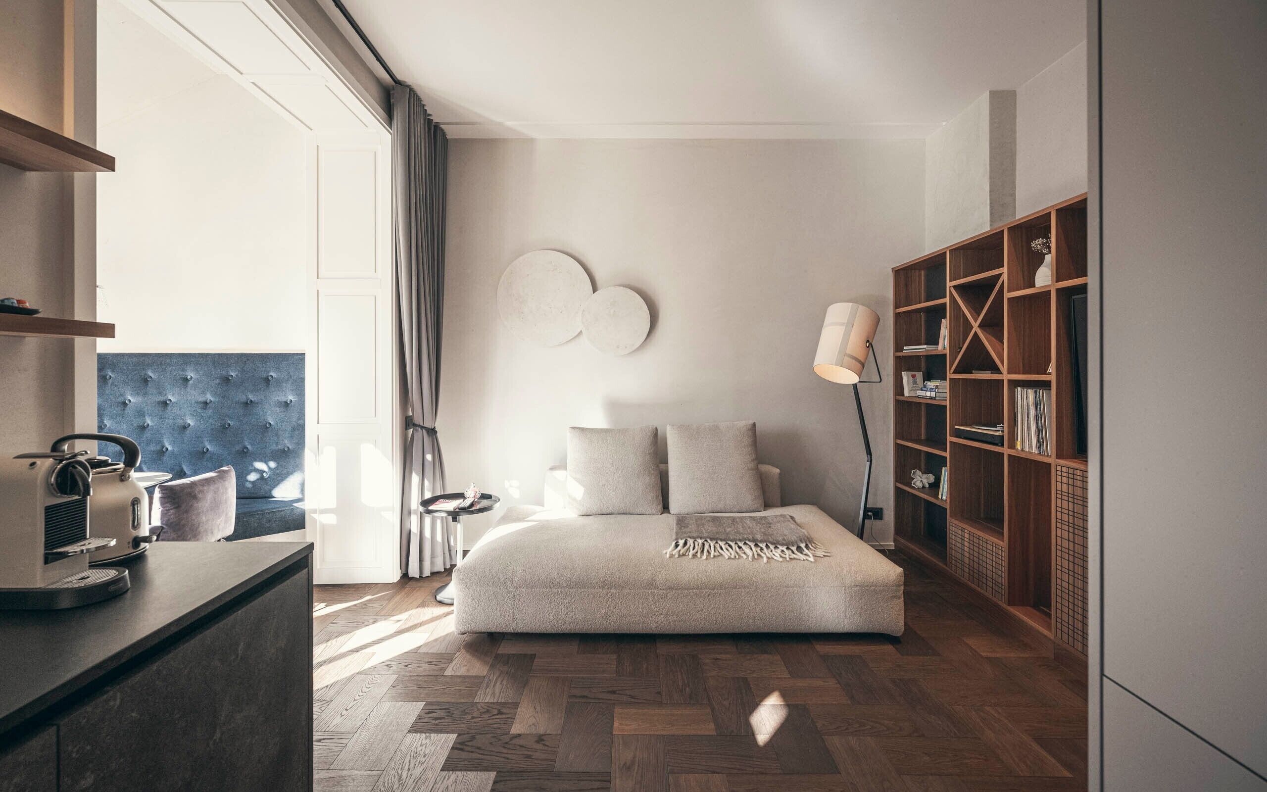 Ett modernt sovrum med en säng, ett sidobord, en bokhylla och ett stort fönster.