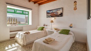 Een kamer met twee bedden, een raam met uitzicht op zeilboten, een schilderij van een landschap en een houten plafond.