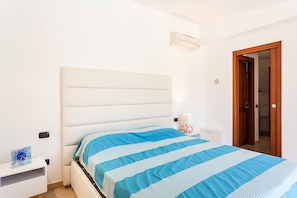 A bedroom with a bed, bedside table, lamp, and a door.