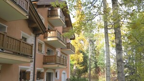A multi-story building with balconies, surrounded by trees and greenery. - Apartment house in a fantastic location with lake view. (St. Moritz)