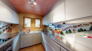 Une cuisine avec un îlot central, une fenêtre avec des rideaux et une fresque murale.
