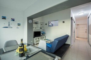 Un soggiorno moderno con un tavolo in vetro, un divano, una TV e un muro decorato con decorazioni a tema nautico.