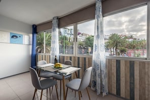 A dining area with a glass table and chairs, a bottle, and a banana on the table.