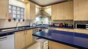 Una cocina moderna con armarios de madera, encimera azul, electrodomésticos de acero inoxidable y una ventana con vidrio esmerilado.