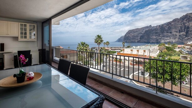 Un balcón con vista al mar y a la montaña.
