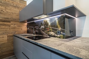A modern kitchen with a built-in stove, wooden wall paneling, and a decorative backsplash.