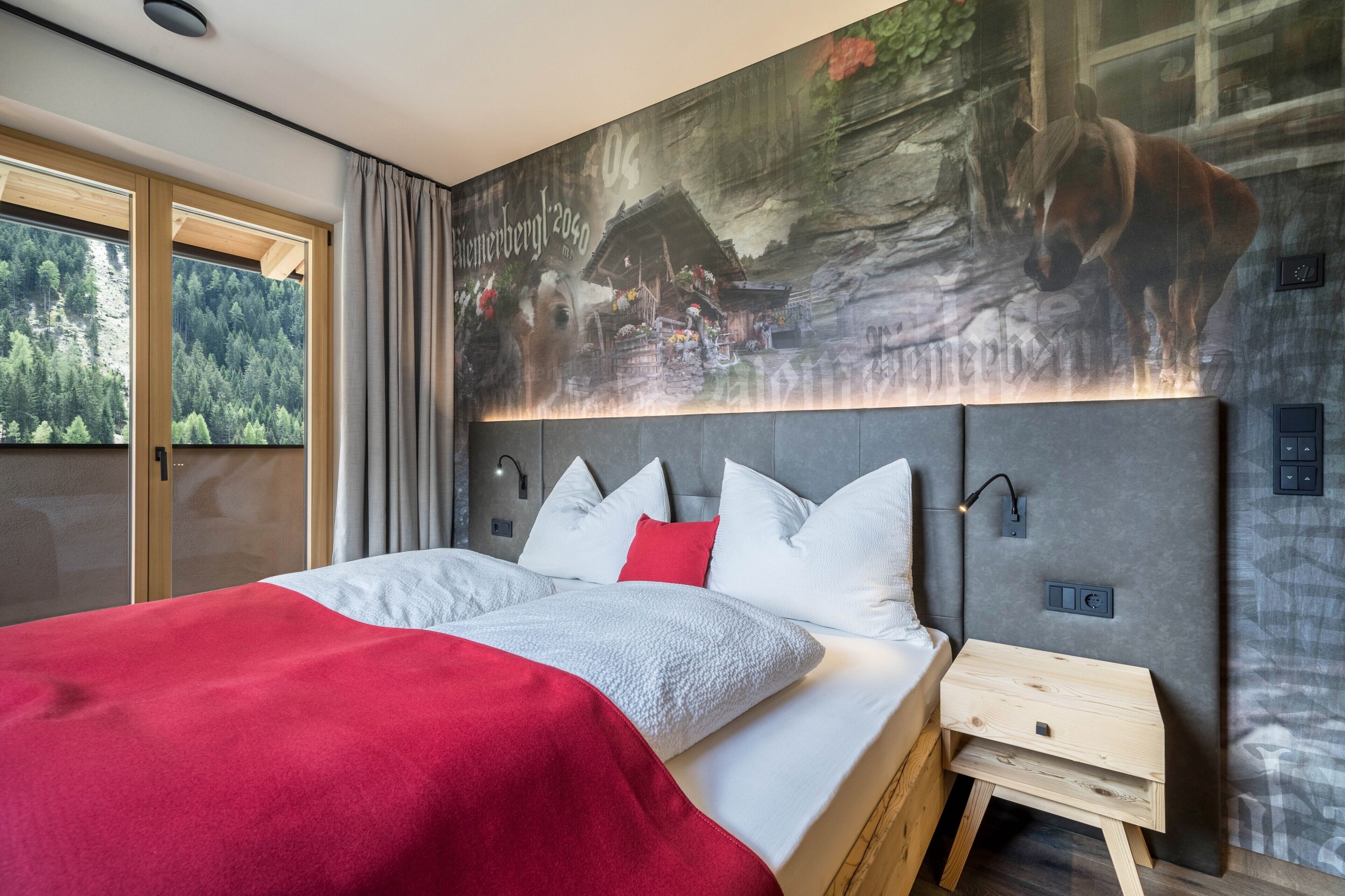 Un dormitorio moderno con una cama grande, un cabecero con iluminación integrada, una mesita de noche pequeña y un mural de un caballo y un bosque.