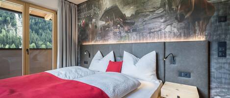 Un dormitorio moderno con una cama grande, un cabecero con iluminación integrada, una mesita de noche pequeña y un mural de un caballo y un bosque.