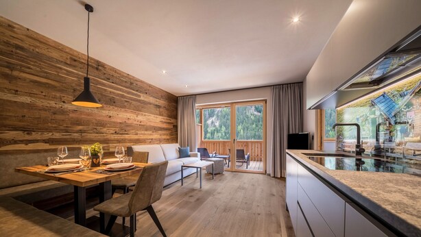 Eine moderne Küche mit Essbereich, Holzwänden und einem großen Fenster.