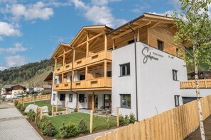 Un hotel de varios pisos con balcones de madera, fachada blanca y vistas a un paisaje montañoso.