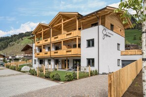 Un bâtiment moderne doté de balcons en bois, d’une allée pavée et d’une enseigne indiquant « Hôtel Alpenblick ».