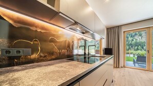 A modern kitchen with a granite countertop, stainless steel appliances, and a decorative backsplash. - Apartment 'Seebrunn - Kuppelwieser Alm' with Mountain View, Private Terrace and Wi-Fi (Ulten)