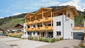 A two-story building with wooden balconies, a white facade, and a paved driveway. - Apartment 'Seebrunn - Kuppelwieser Alm' with Mountain View, Private Terrace and Wi-Fi (Ulten)