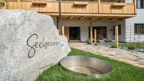 A stone with 'Seeborn' engraved, a metal basin, and a wooden balcony of a building. - Apartment 'Seebrunn - Kuppelwieser Alm' with Mountain View, Private Terrace and Wi-Fi (Ulten)