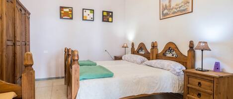 A bedroom with a wooden bed, a nightstand, a wardrobe, and three framed pictures on the wall.