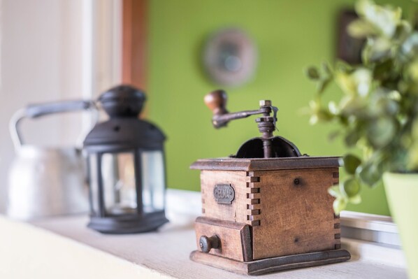 A wooden grinder with a handle and a dial, a black lantern, and a green wall in the background. - Country House "Finca Carrillo" with Sea and Mountain Views (Arico)
