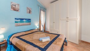 A bedroom with a bed, a wardrobe, a nightstand, and a painting on the wall. - Holiday Home “Home Residence Barbara” with Garden & Balcony (San Teodoro)