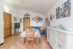 Un coin repas avec une table dressée pour quatre personnes, un canapé et un meuble contenant des objets décoratifs.
