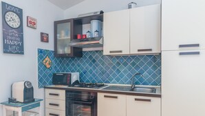 A kitchen with white cabinets, a microwave, a stove, and a coffee maker. - Holiday Home “Home Residence Barbara” with Garden & Balcony (San Teodoro)