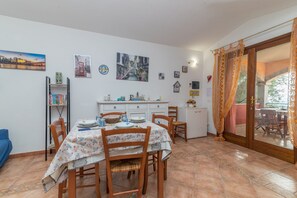 A dining area with a table set for four, a bookshelf, and a kitchen area with cabinets and a sink.
