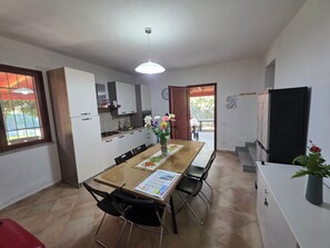 A modern kitchen with white cabinets, a dining table with chairs, and a refrigerator.
