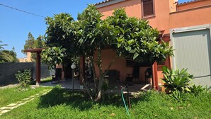 A residential building with a patio area, a water hose, and a carport. - Villa "Giulia Grande" in rural area near the sea with mountain view and garden (Castiadas)