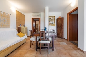 Una stanza con un letto, un tavolo da pranzo con sedie, un armadio in legno e una mensola a parete.