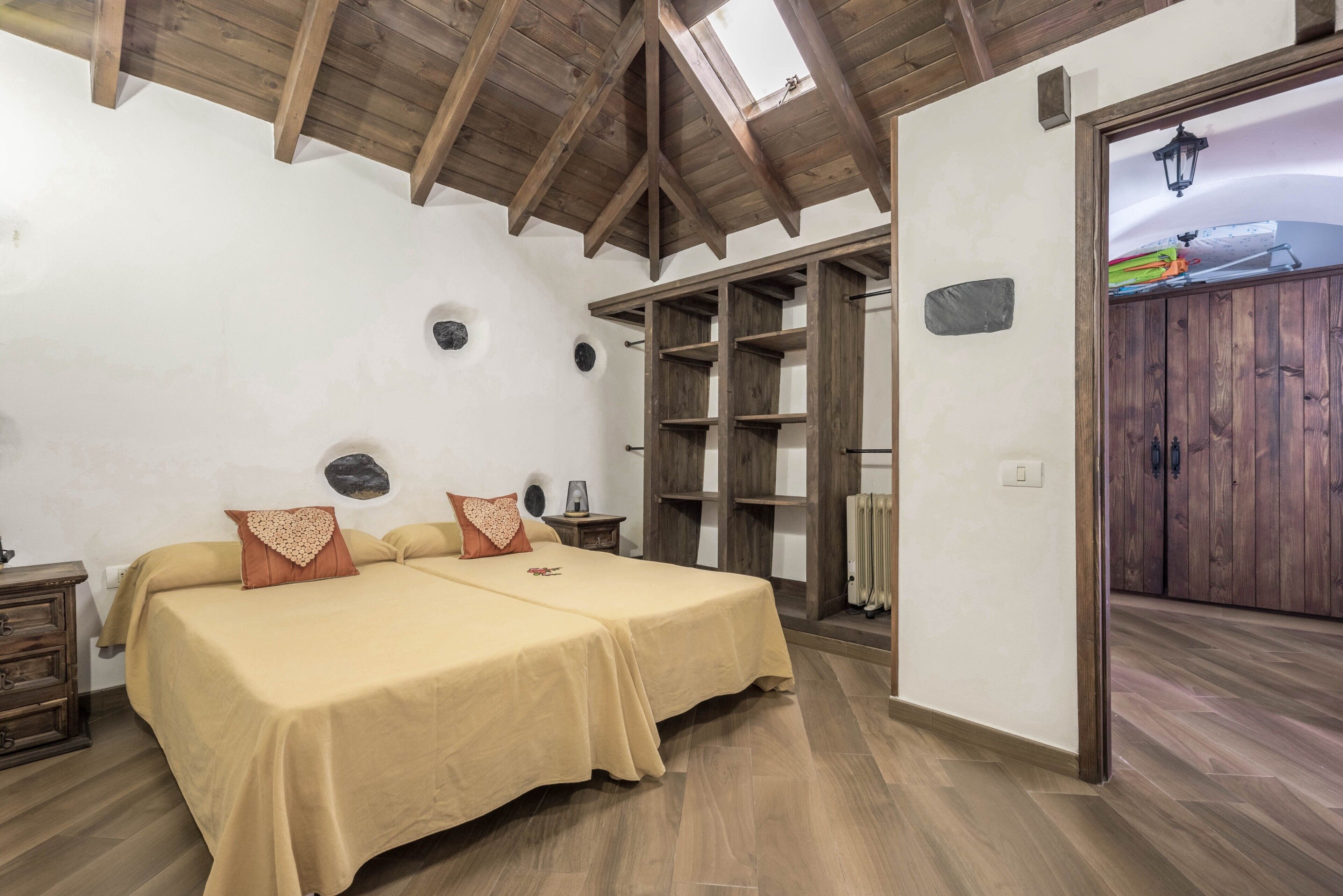 Ein Schlafzimmer mit Holzboden, einem Bett mit beigefarbener Bettwäsche, einem Nachttisch und einem Kleiderschrank.