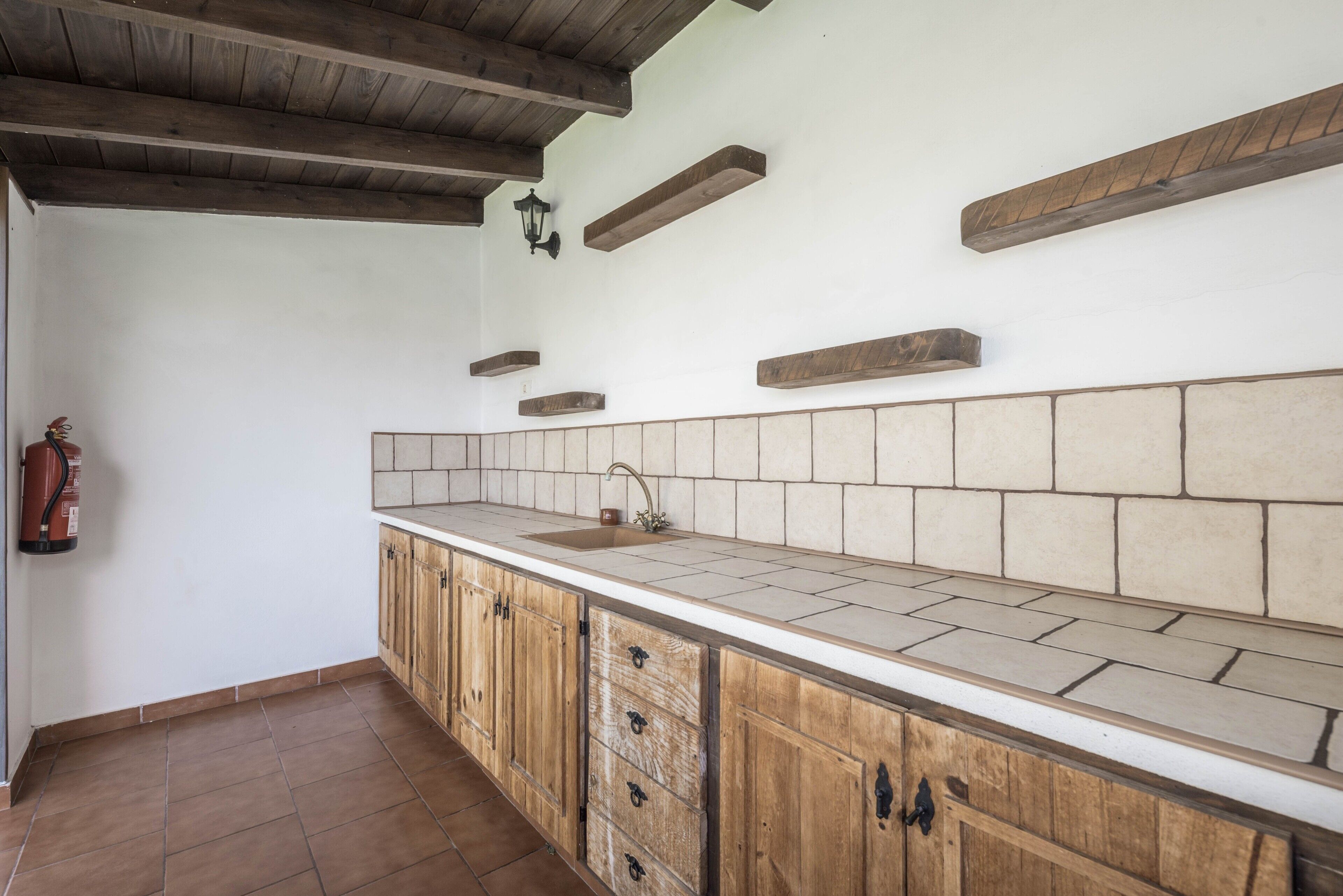 Une cuisine avec un mur recouvert de carreaux, des armoires en bois et un plafond en bois.