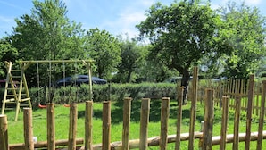 Une clôture en bois avec une échelle et des balançoires dans un parc.