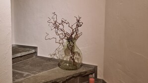 Un escalier en pierre, et sur le palier, un vase en verre contenant une plante.