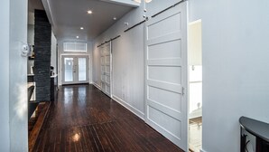 Un couloir doté d’un plancher en bois, d’un mur d’accent en pierre et d’un lustre moderne.