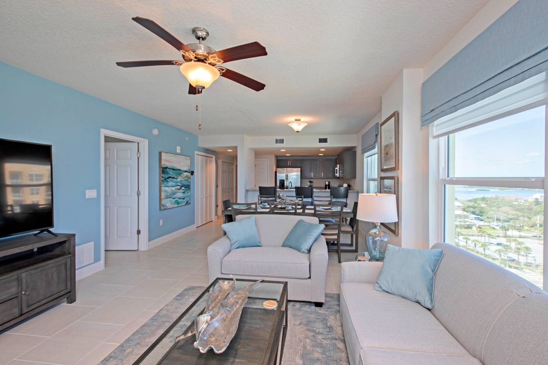 A spacious living room with a ceiling fan, a flat-screen TV, and a dining area with a table and chairs.