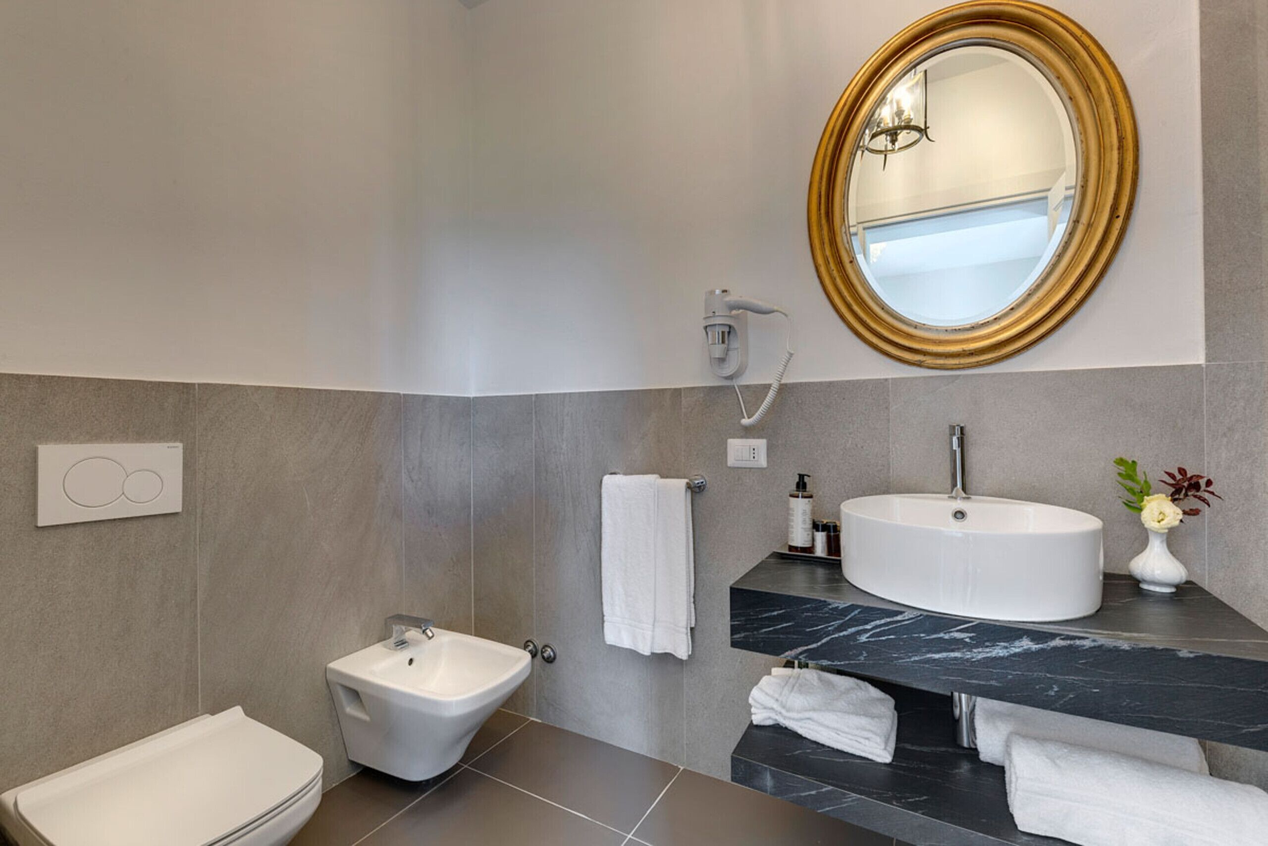 A modern bathroom with a toilet, bidet, and a large sink with a marble countertop.