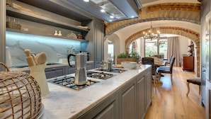 A modern kitchen with a marble countertop, built-in appliances, and an archway leading to a dining area. - Ville Il Paradiso with Private Pools, Garden, Terraces, Ideal for Weddings (Panzano)