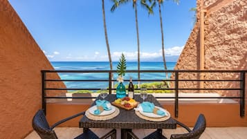 A table set for two with a view of the ocean and palm trees.