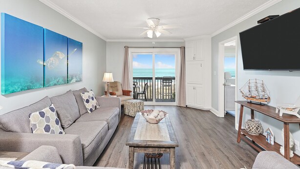 A living room with a view of the ocean, a ceiling fan, and a television. - Condo w/ Private Balcony & Stunning Beach Views (Surfside Beach)