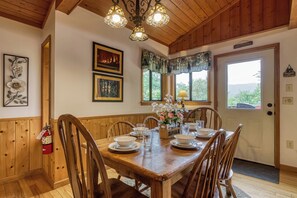 Ein Esszimmer mit Holzboden, einem Tisch für vier Personen, gerahmten Bildern an der Wand und einer Tür mit einer Willkommensschild.